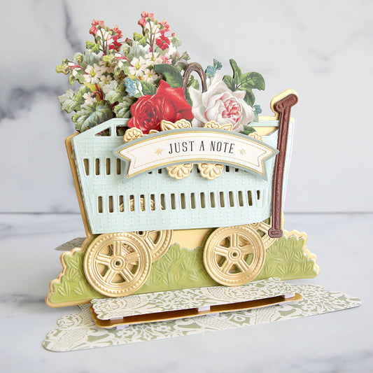 Layered wagon card with flowers, green vellum, and gold accents.