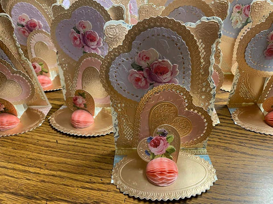 a table topped with lots of pink and gold cards.