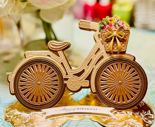 a gold and brown bicycle with basket of colorful flowers