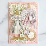 2 pink Victorian dresses on an embossed card with flowers