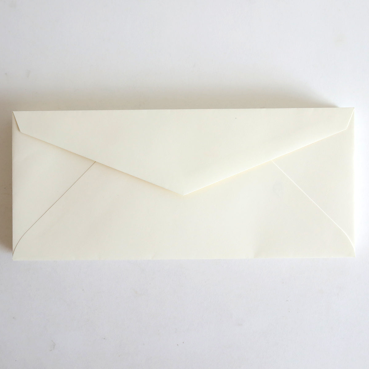 A closed, natural 4.125" x 9.5" envelope from the 25 Pack rests on a white surface, evoking the timeless elegance of Classic Crest envelopes.