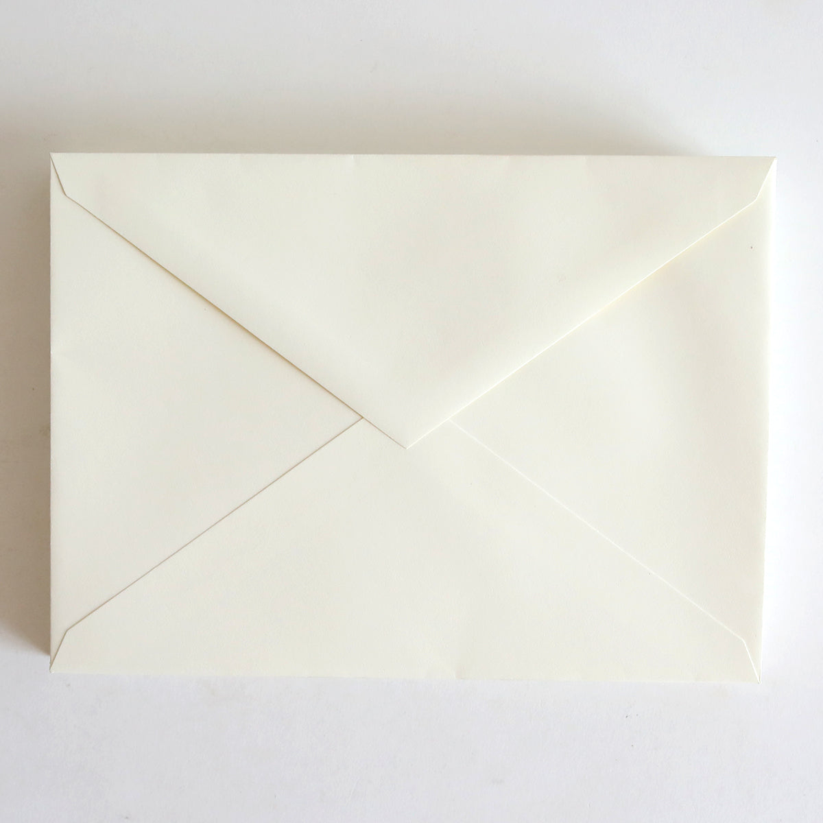 A 25 Pack of natural envelopes, each measuring 5.25" x 7.25", featuring a pointed flap, rests on a white surface.