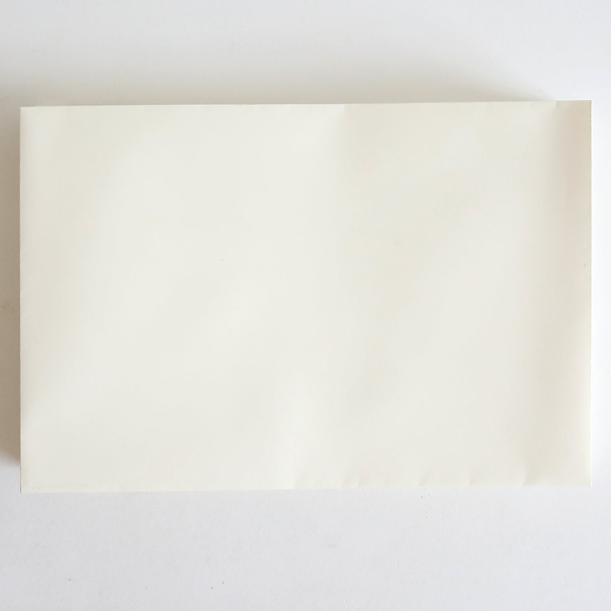 A blank white sheet rests on a white surface, evoking the classic elegance of the 25 Pack Natural Envelope 8.125" x 5.5".