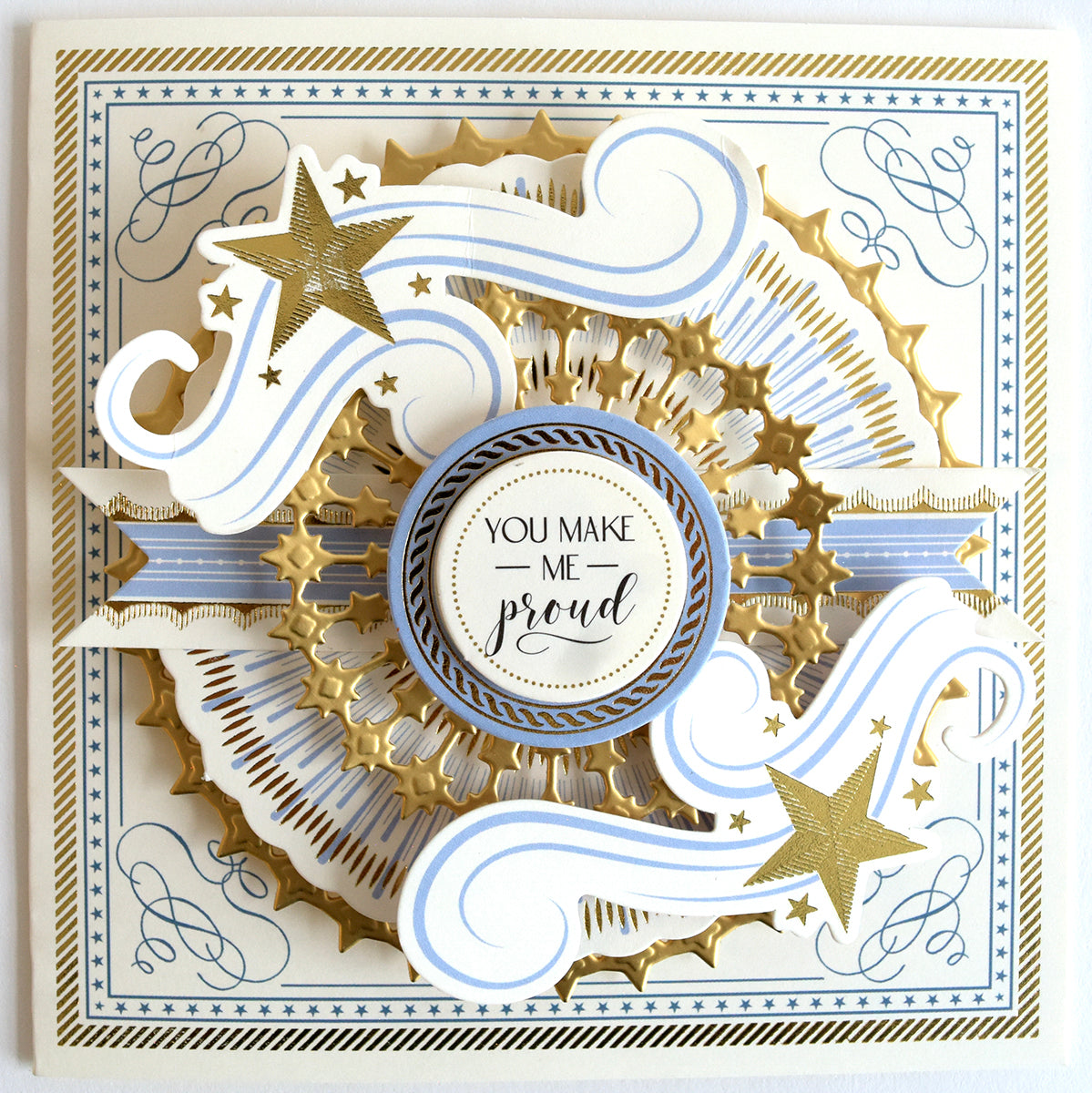 Elaborate 3d paper art card with gears and ribbons in gold and cream, featuring text "you make me proud" encircled at the center, adorned with Celebration Chest Embossing Folder with Dies accents.