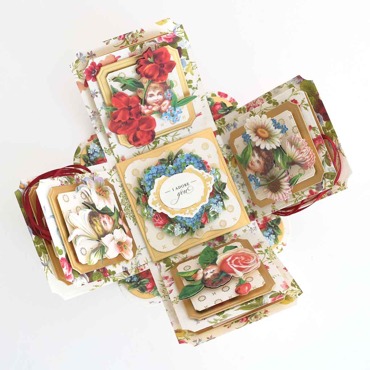 A floral-themed pop-up card made with Explosion House Dies and Materials, featuring vintage-style flower illustrations, die-cut embellishments, and a central "I adore you" message.
