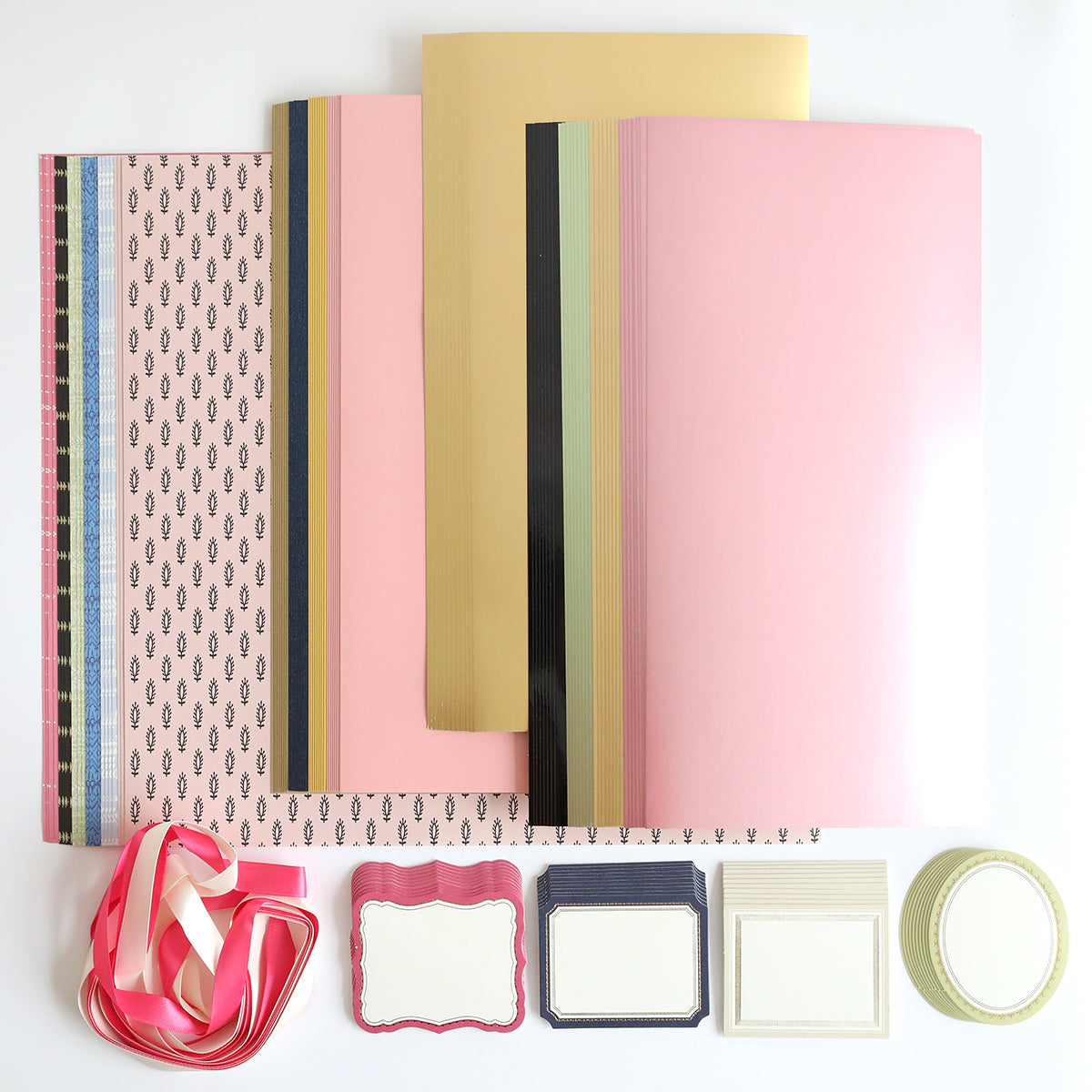 The Crop at Home 3 Swag, a collection of stationery items ideal for cardmaking or scrapbooking, features patterned papers, ribbons, and labels beautifully arranged on a white background.