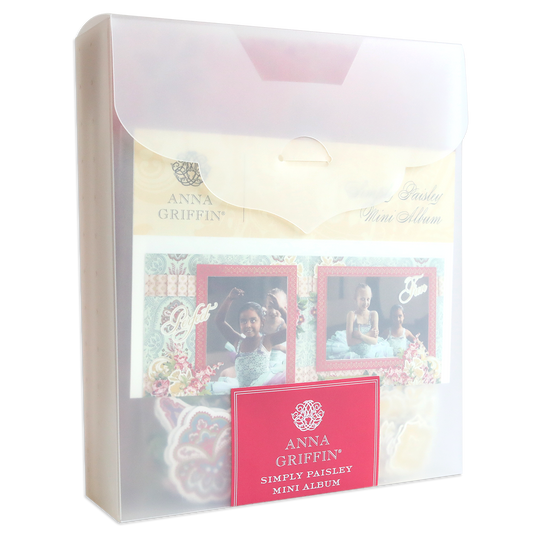 A translucent plastic case holds the Simply Paisley Mini Album and Materials, showing decorative pages, photo mats, and a red front label.
