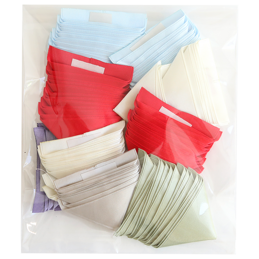 The "Satin Ribbon Corners" set includes a clear plastic bag with folded cloth face masks in red, light blue, white, light green, and lavender, each featuring satin ribbon corners for added comfort and style.