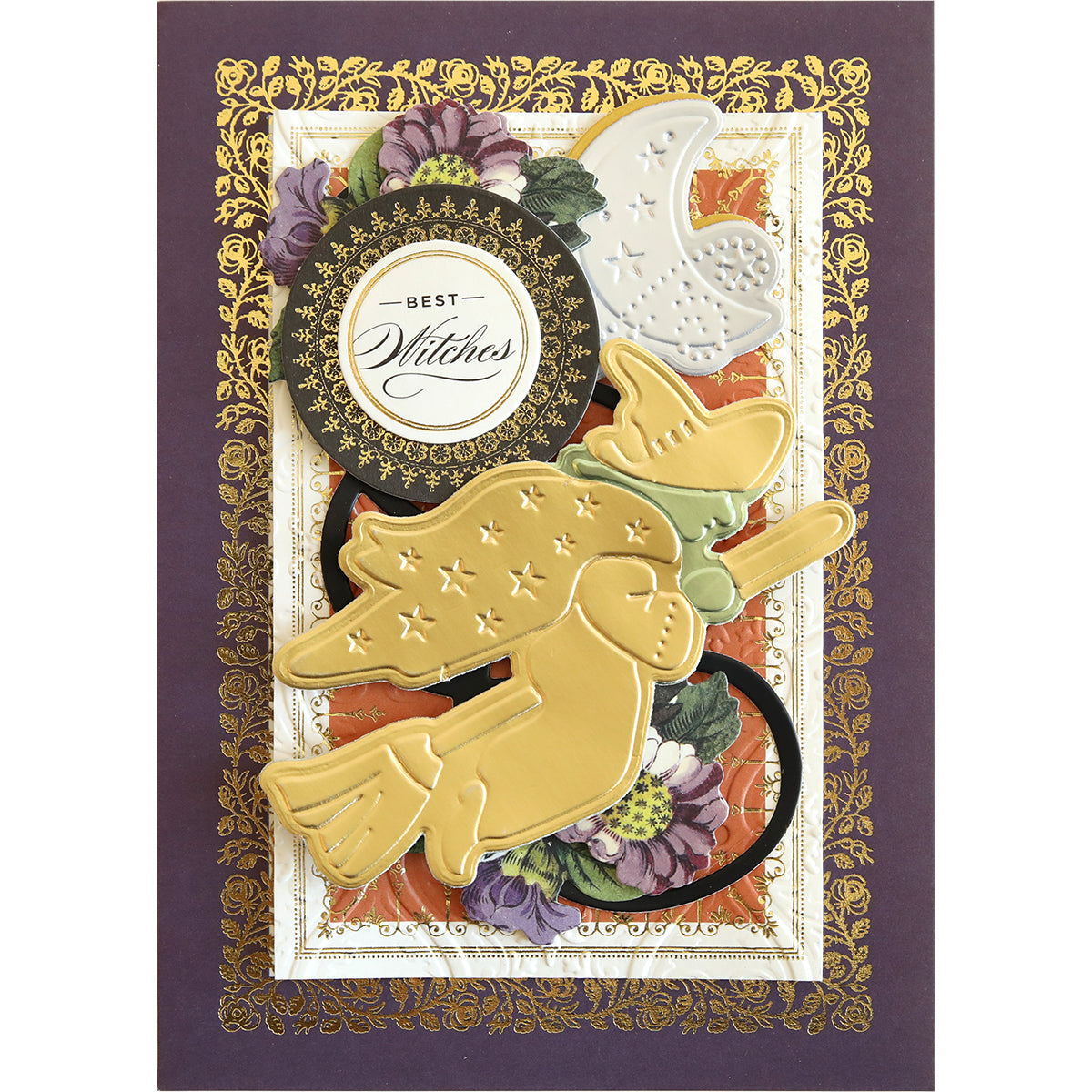 A decorative Halloween card featuring the "Spooktacular Friends Cut and Emboss Folders," adorned with golden witches on brooms, a silver moon, intricate floral patterns, and "Best Witches" written at the center.