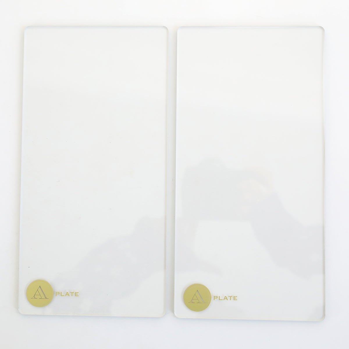 Two Empress Elite Mini 5" x 10" clear glass plates, each with a gold circular label marked "PLATE" and an "A" in a triangle in the bottom left corner, are placed side by side on a white surface. Set of 2 A Plates.