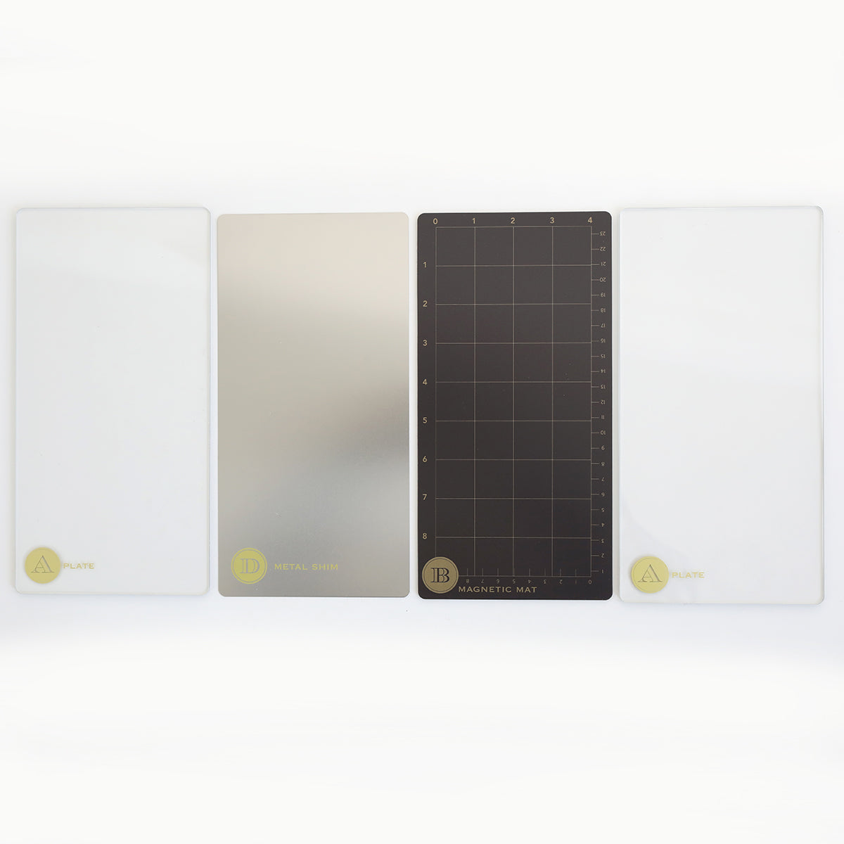Four rectangular die cutting plates—two clear, one metallic, and one black with a grid—are aligned side by side as the Empress Elite Mini 5" x 10" Full Plate Set from Anna Griffin.