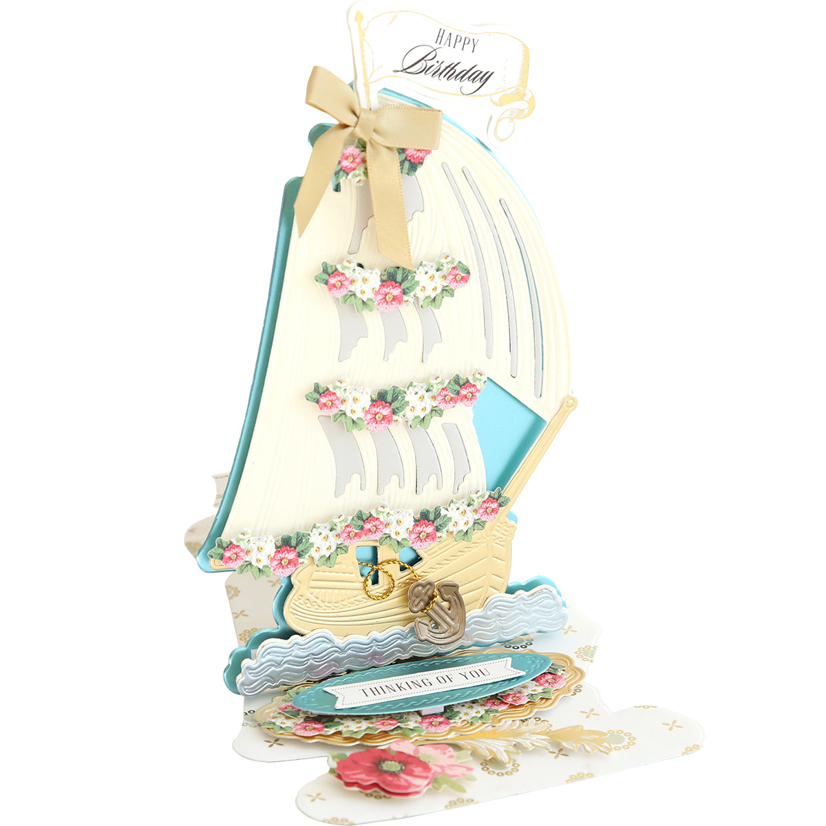 The pop-up birthday card, crafted with Schooner Easel Dies, features a sailboat adorned with floral decorations and gold accents. It includes the message "Thinking of You" and is ideal for mariners who appreciate nautical elegance.