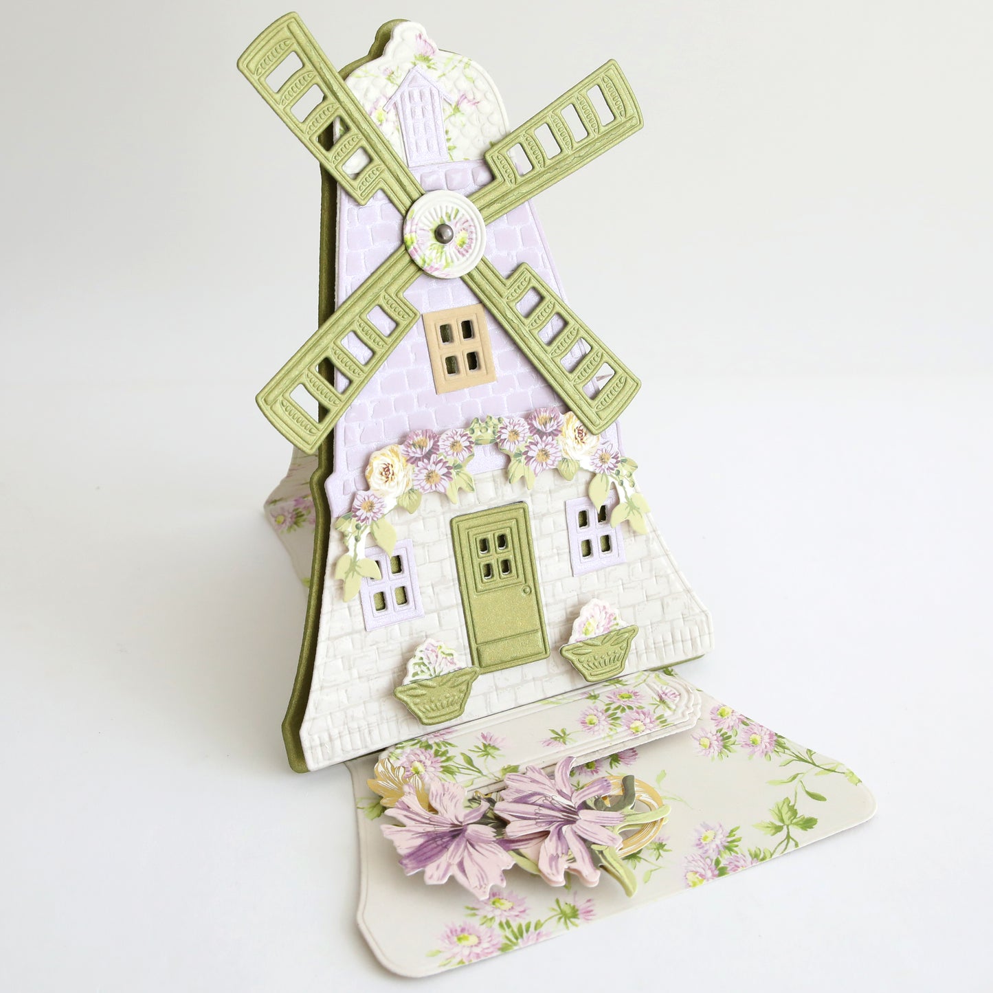 A pastel windmill pop-up card, made with Windmill 12x12 Cardstock and easel dies, features floral and window details and is displayed on a white background.