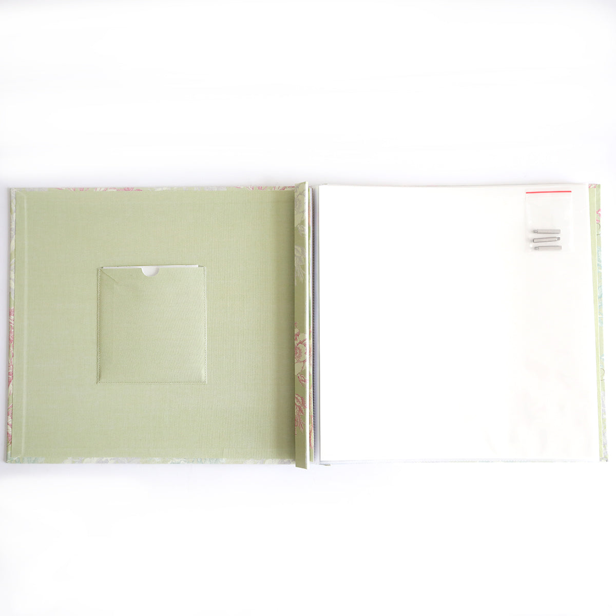 The Antique Botanical Scrapbook Album features a green inside cover with a left pocket and blank white pages secured by metal binder rings and screws on the right, all in a plastic bag—ideal for adding page protectors.