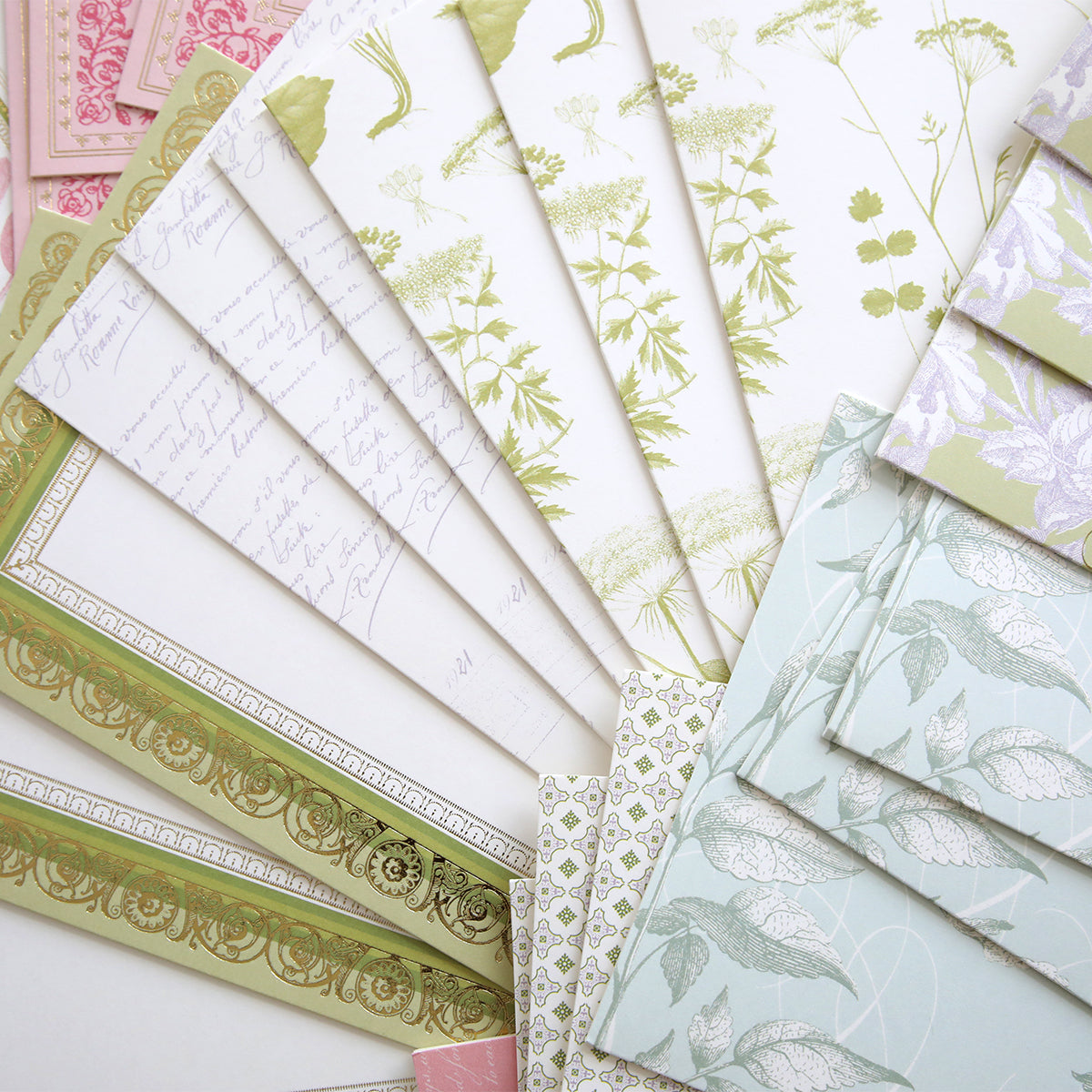 The Antique Botanical Cards and Envelopes set features decorative stationery and envelopes with beautiful patterns and soft pastel hues, all arranged in a fan shape for a charming vintage touch.