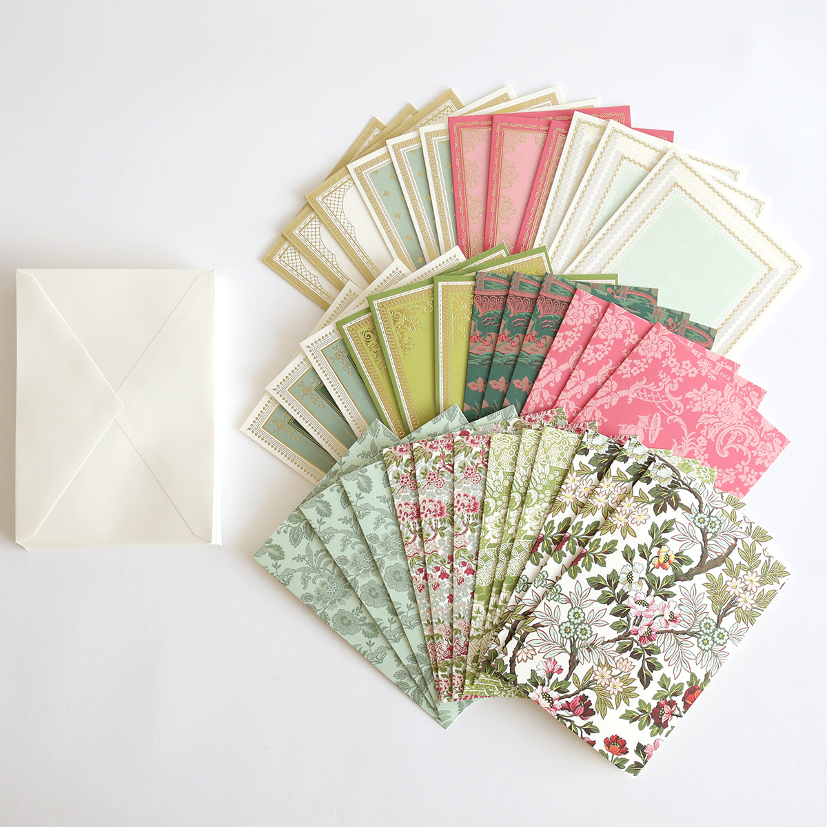 Lian Cards and Envelopes features handmade cards in green, pink, and cream with beautiful patterns, fanned out beside a white envelope on a white surface.