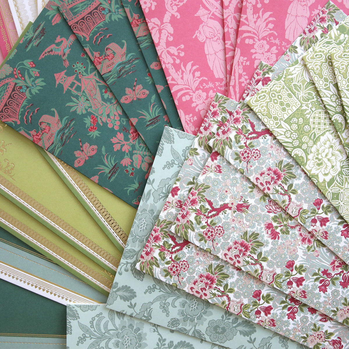 A variety of patterned wallpaper samples in pink, green, and blue are arranged in a fan shape, ideal for crafting unique handmade cards with Lian Cards and Envelopes.
