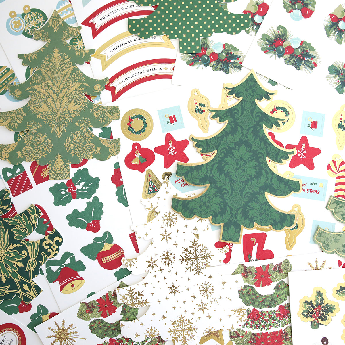 Tree Shaped Cards and Embellishments feature assorted Christmas-themed paper cutouts, like decorated trees, holly, ornaments, and festive banners—perfect for holiday greeting cards—arranged on a white surface.
