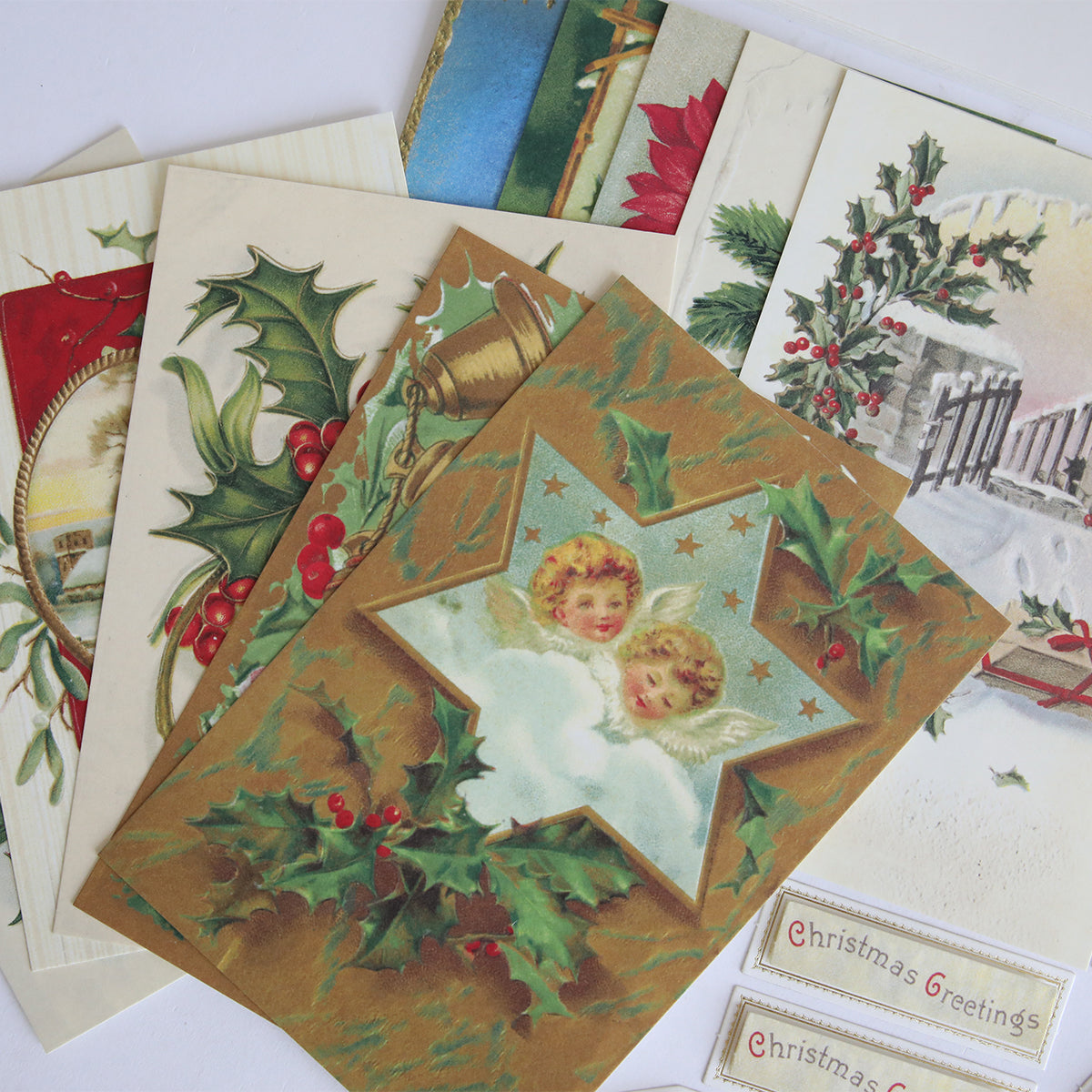 The Christmas Postcard Card Making Kit features vintage designs with holly, festive scenes, and two angels in a star—perfect for crafting unique holiday greeting cards.