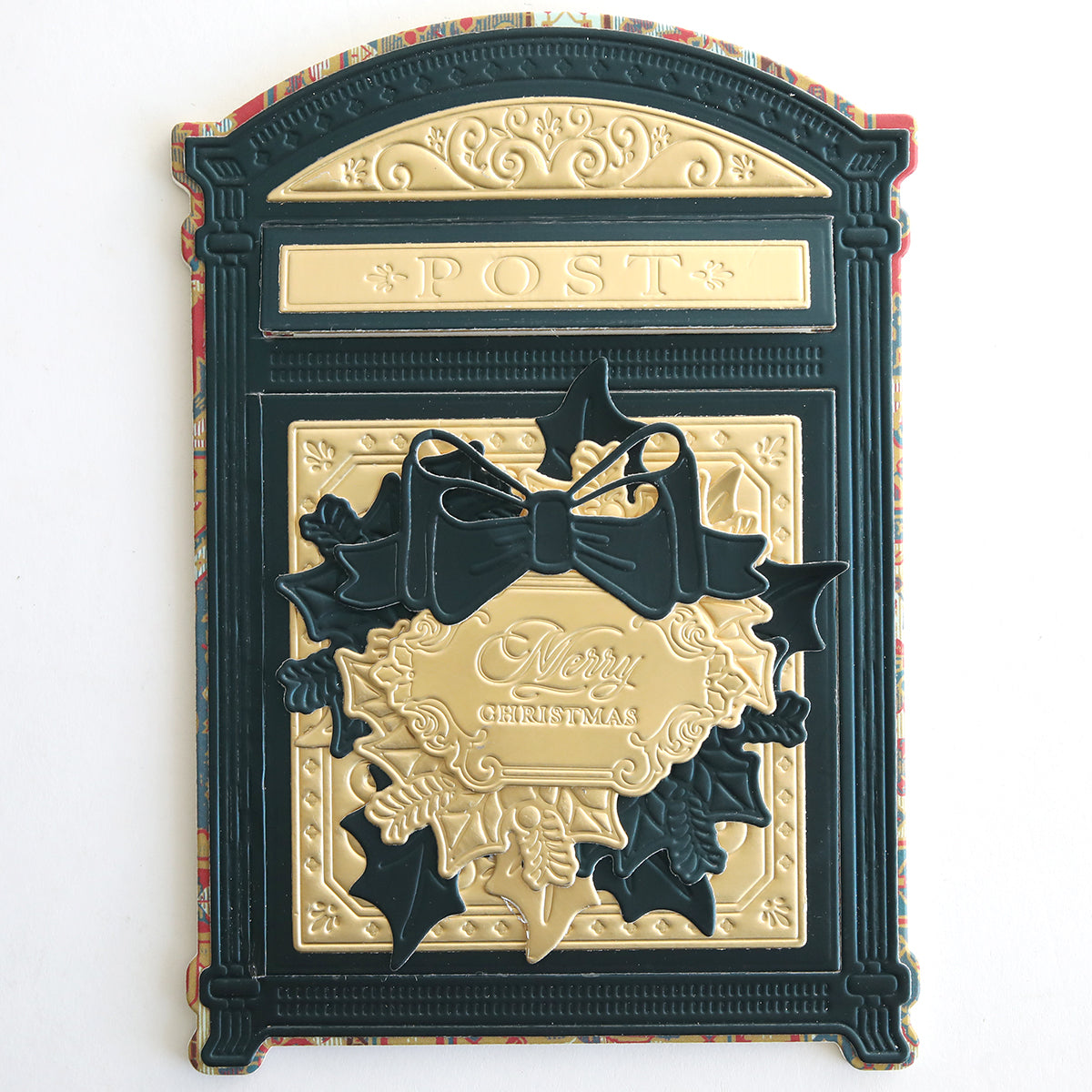 A decorative gold and dark green card, crafted from Jasmine Matte Foil Cardstock and shaped like a vintage postbox, features "POST" at the top and "Merry Christmas" embossed with holly and a bow in the center.