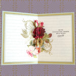 An open greeting card with a floral design and a blessing message surrounded by decorative paper.
