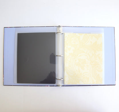 An open Astrid Floral Magnetic Die Storage Binder with one transparent sleeve and one patterned yellow page against a white background, perfect for crafting organization.