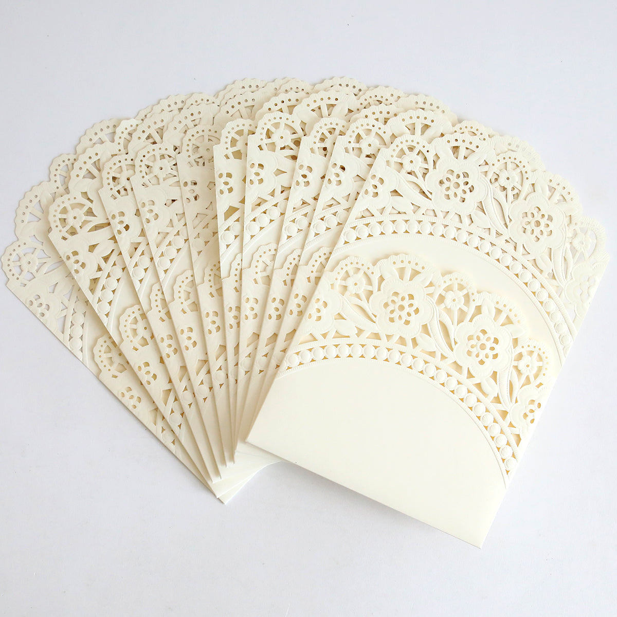The Ivory Double Scallop Lace Pocket 10 pack features intricately designed ivory laser-cut envelopes with floral patterns and elegant double scallop edges, ideal for wedding invitations, shown fanned out on a white background.