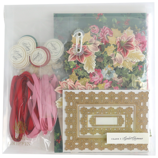The Eyelet Elegance Dies and Materials kit includes floral paper, decorative frames, satin ribbons, seals, a metal clasp, and elegant embellishments, all neatly arranged in a clear plastic bag.