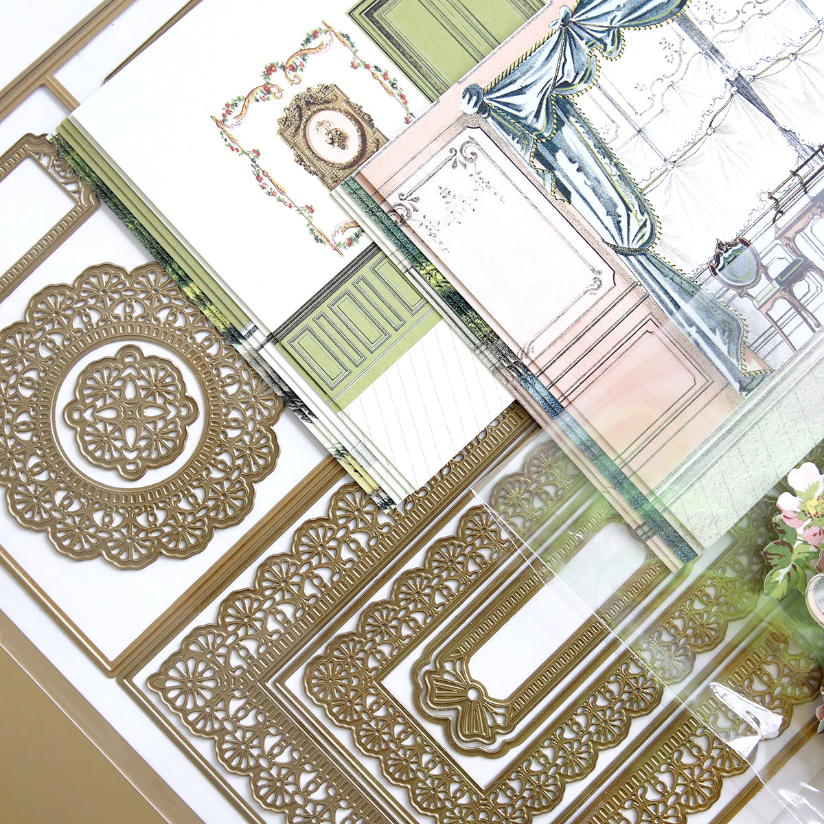 Theatrical Greetings Dies and Materials are arranged on a table with various ornate cardstock designs and intricate metallic die cut patterns.