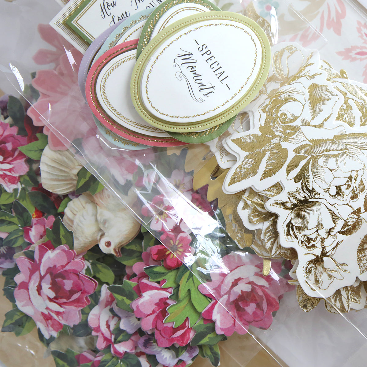 Discover the Corset Album Dies and Materials, a collection featuring decorative cards and floral cutouts with pink peonies, gold-etched designs, and intricate embellishments.