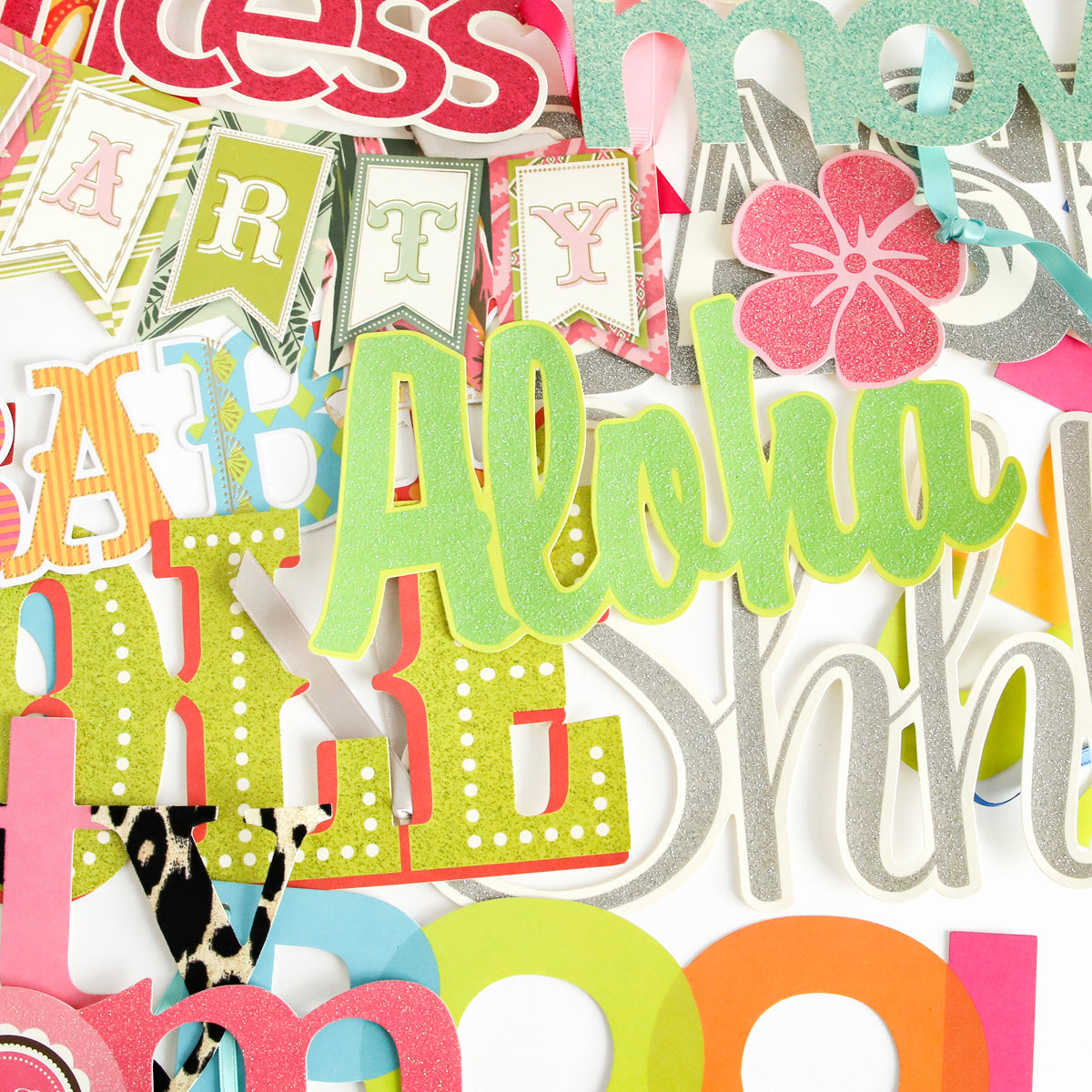 Add a vibrant touch to handmade cards or scrapbook pages with the Party Time Diecut Word Assortment—featuring colorful cutout letters and banners, including "Aloha" in green glitter, arranged in a layered, overlapping style.