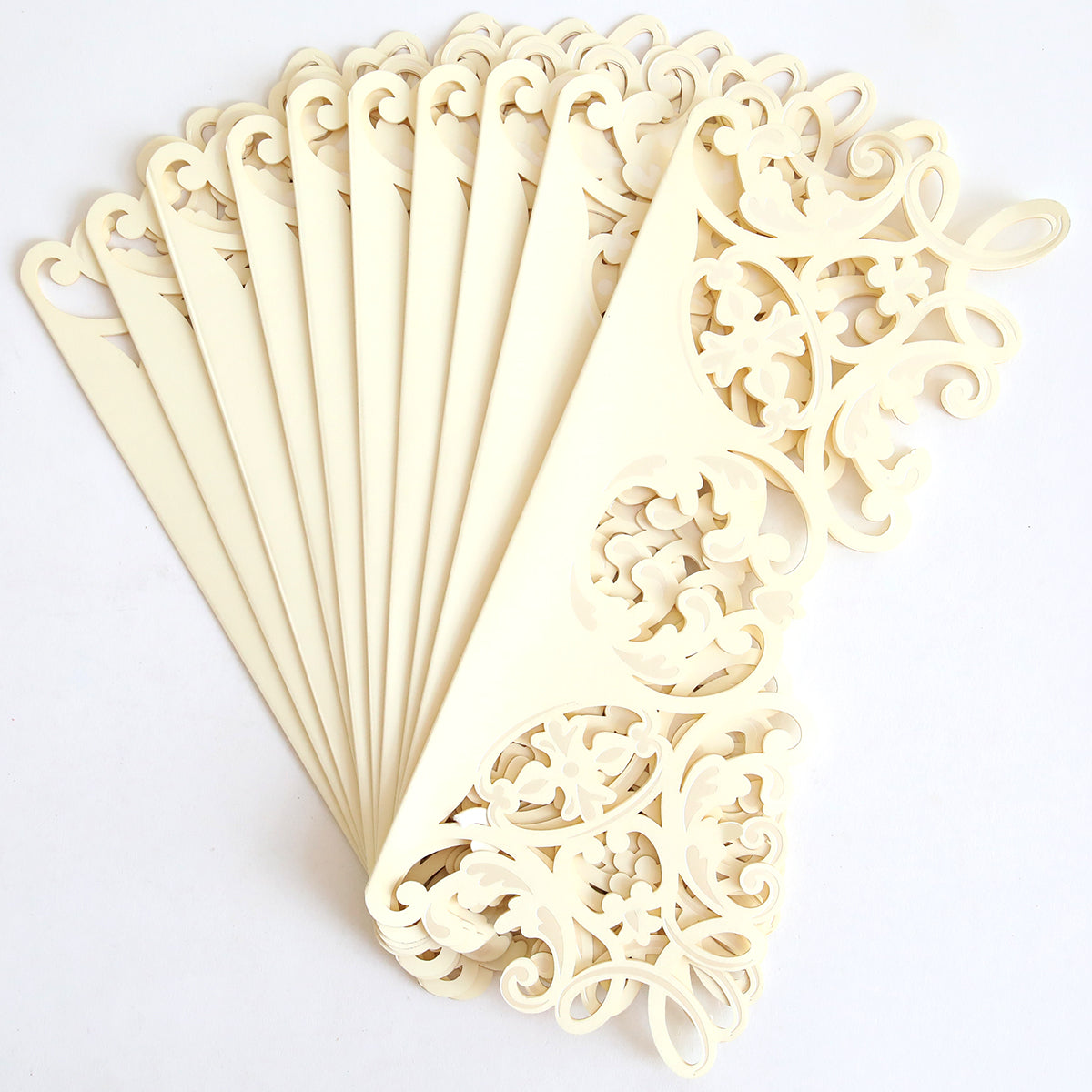 A set of Ivory Filigree Diecut Wraps (10 pack) in cream, intricately cut with elegant ivory filigree, is fanned out in a semicircle on a white background.