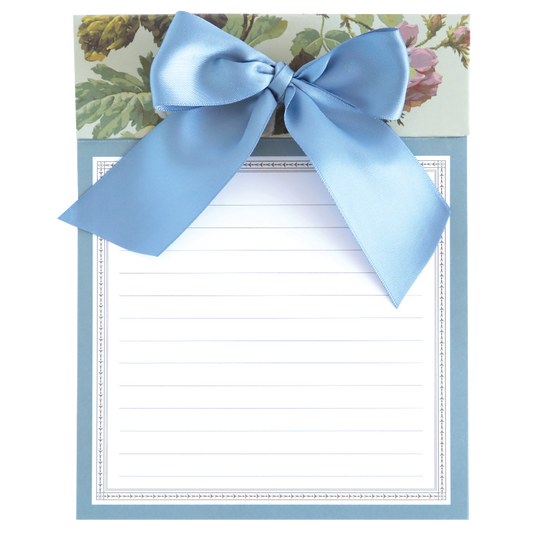 The Francesca Bow Pad is a notepad with a floral design background, perforated sheets, and a decorative blue ribbon on top.