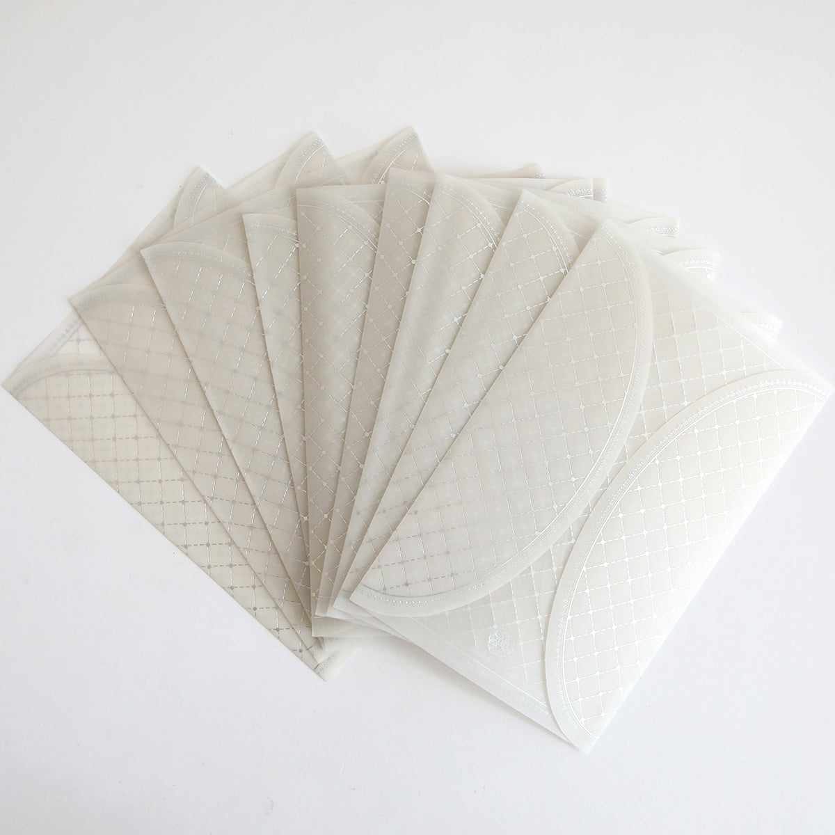 A 10-pack of Silver Foil Harlequin gatefolds with a translucent, patterned finish fanned out on a white surface, ideal for creating elegant wedding invitations.