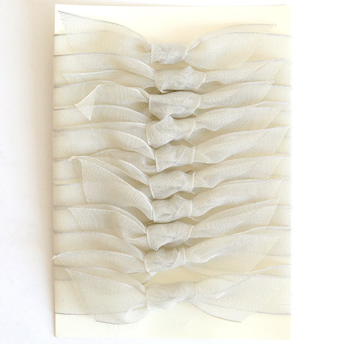 Ten silver mesh knots, each 1" wide, are neatly arranged in two vertical columns on a rectangular cream-colored card.