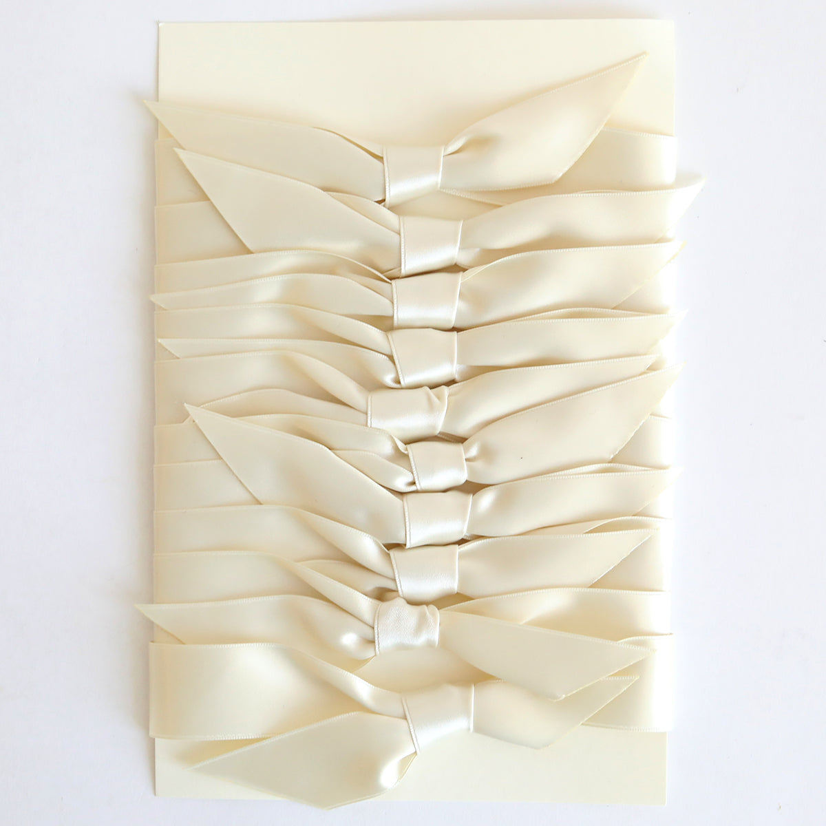 A stack of Ivory Satin Knots 10 count handmade cards, each tied with double-faced satin bows, arranged vertically on a white background.