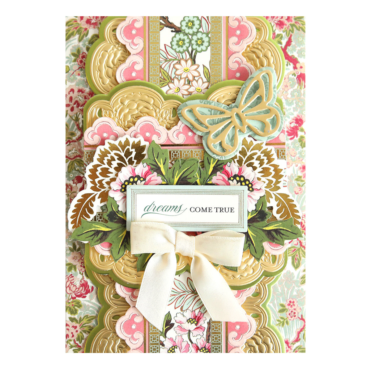 The Lian Ultimate Papercrafting Collection offers a decorative card featuring floral patterns, layered gold and pink design, a butterfly, white bow, and "dreams come true" message—ideal for gifting with an exotic touch.