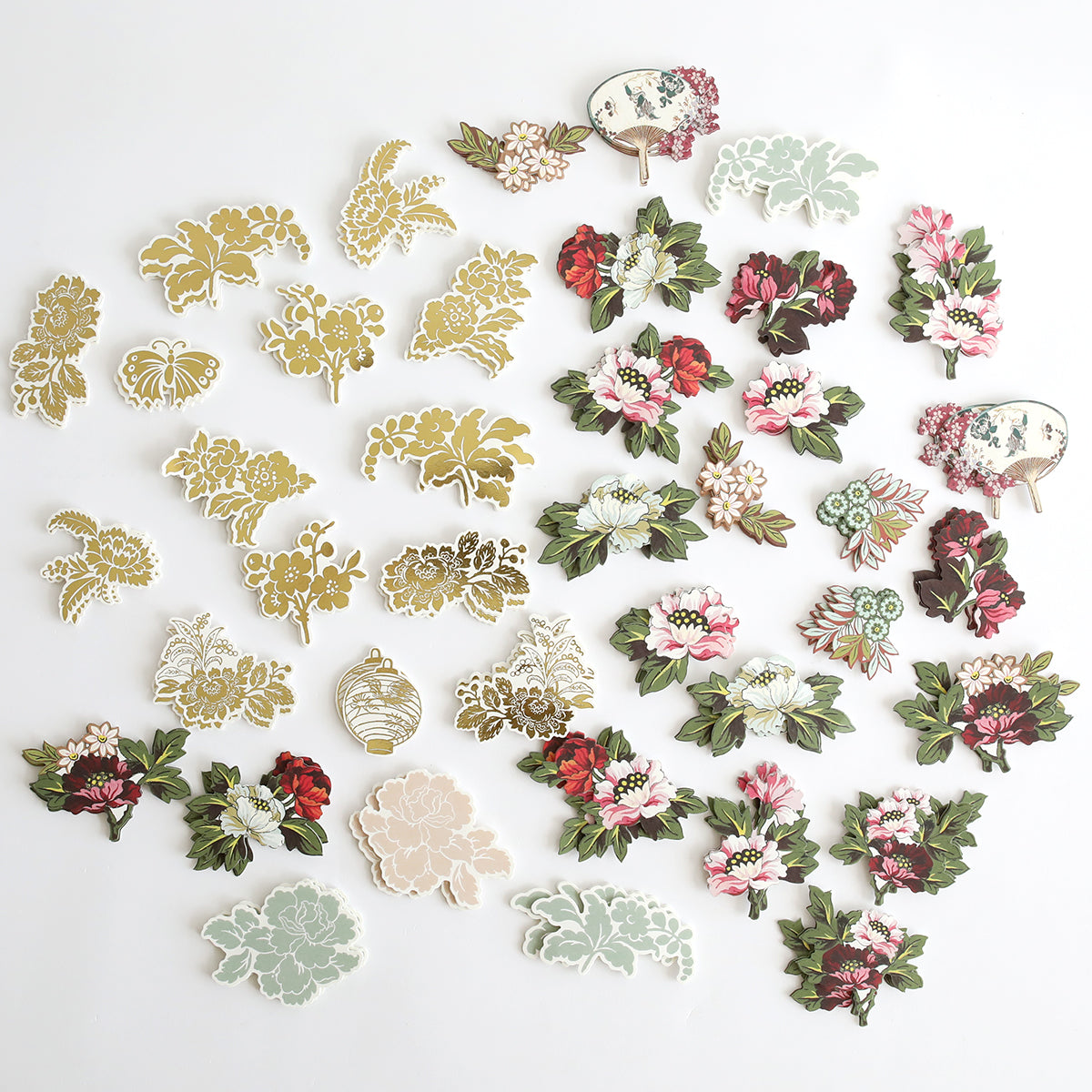 An assortment of decorative floral and botanical paper cutouts from Lian Embellishments, including elegant stickers, artfully arranged on a white surface.