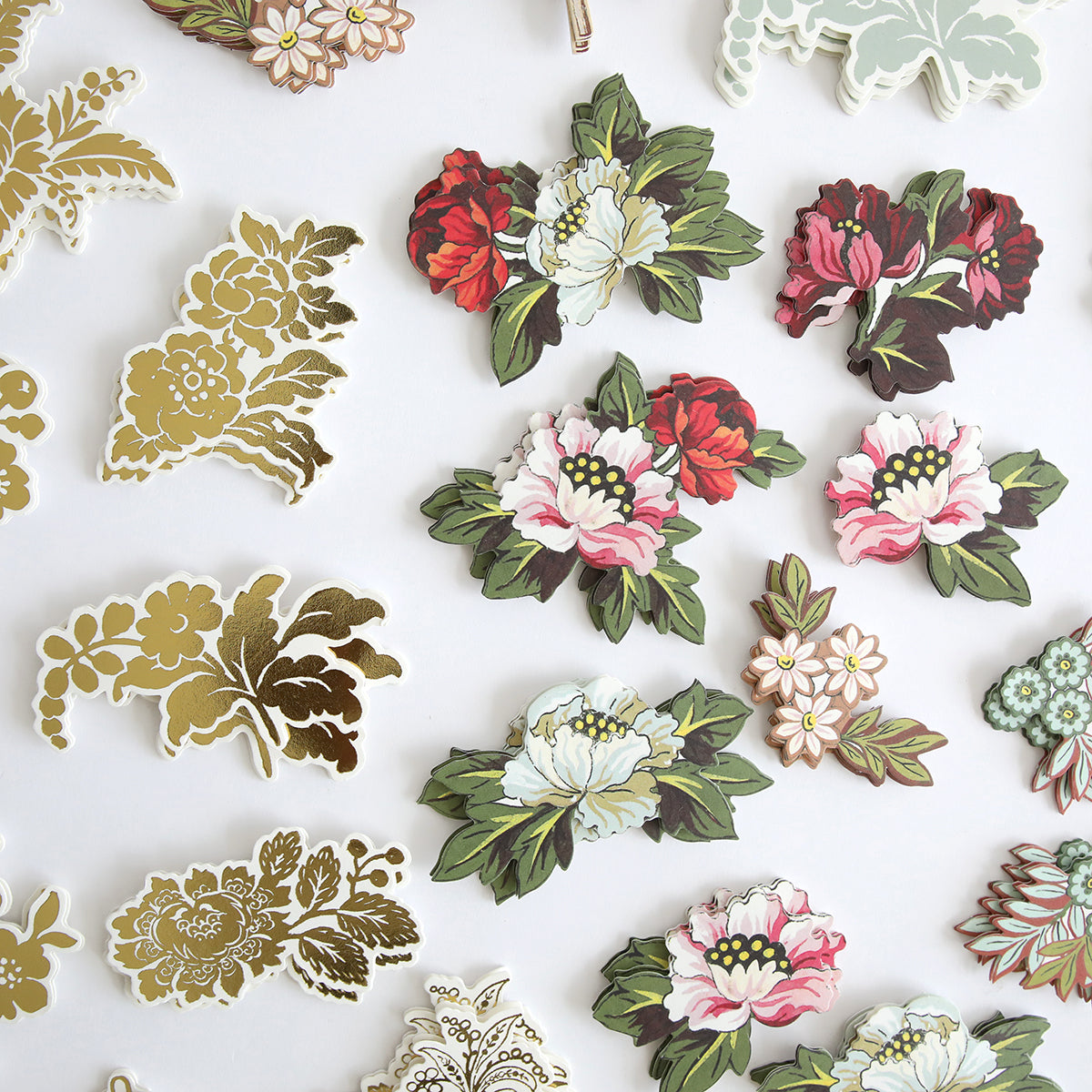 Lian Embellishments from the Francesca Collection feature gold-foil designs and colorful illustrated flowers, all arranged on a white background.