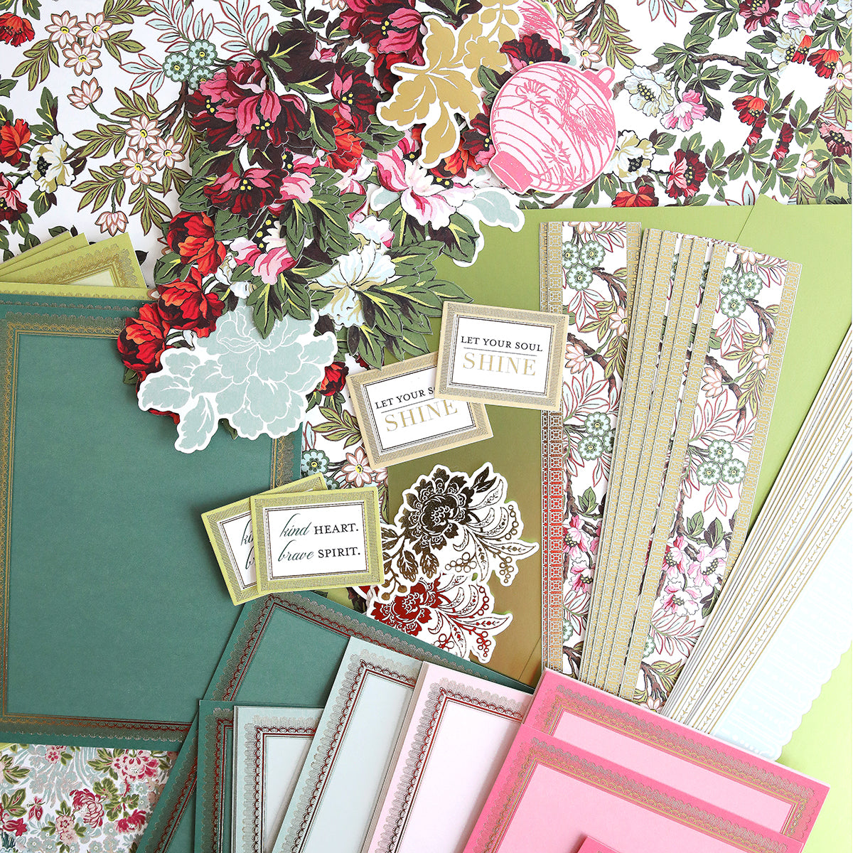 A collection of floral-patterned papers, green and pink cards, and inspirational quotes arranged on a flat surface.