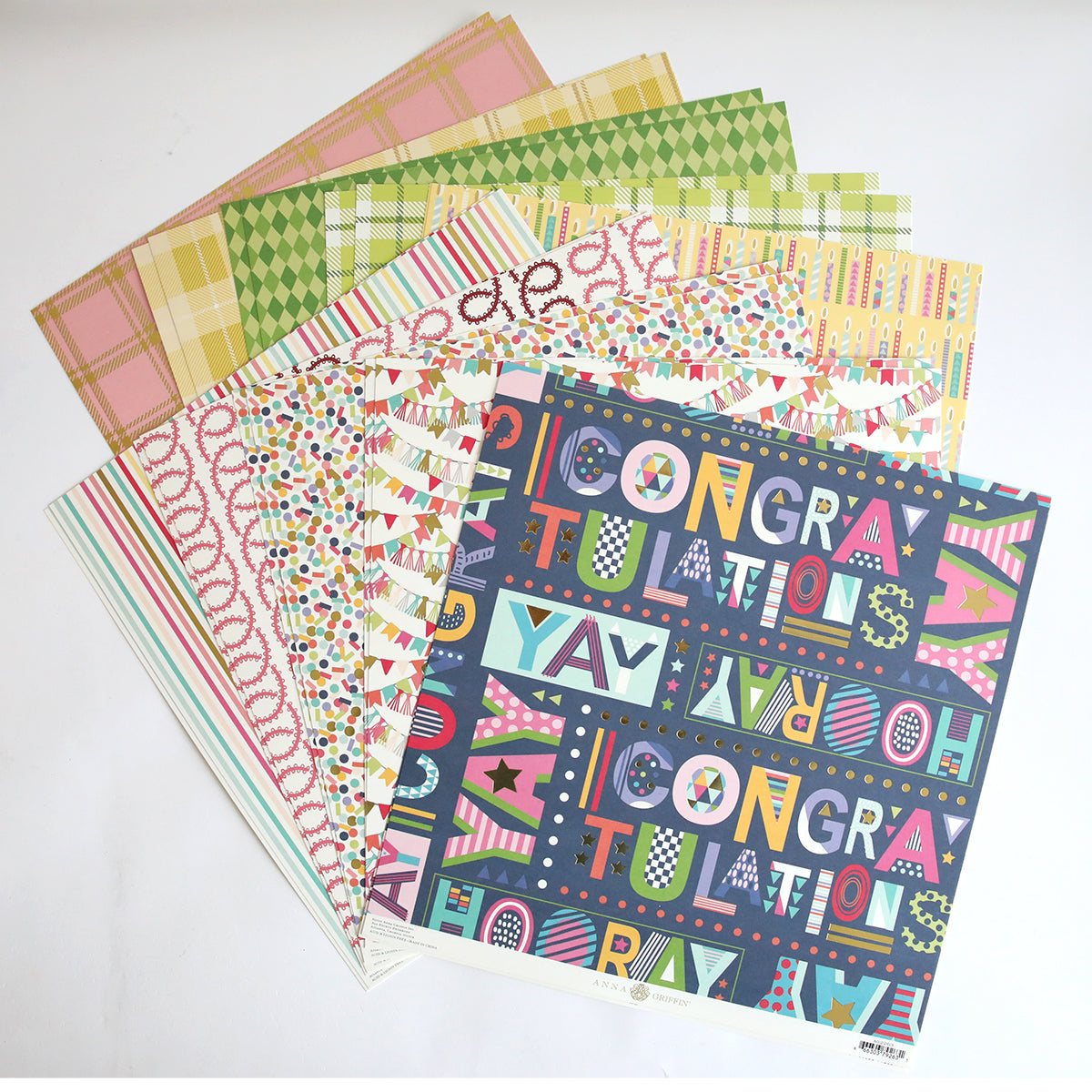 A stack of Mystery Birthday 12x12 Cardstock sheets, featuring vibrant patterns and "Congratulations" text with geometric designs—ideal for creative birthday crafting projects.