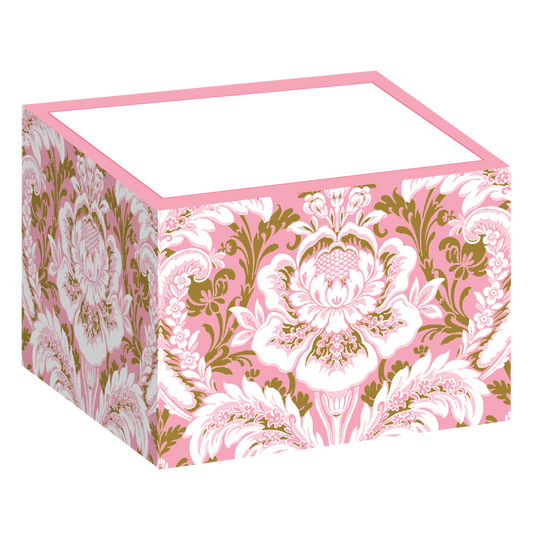 The Pink Damask Notepad Block is a decorative pink box with a floral design featuring large, intricate white and gold flower patterns reminiscent of damask. It has a plain white top and can hold sticky note sheets inside.