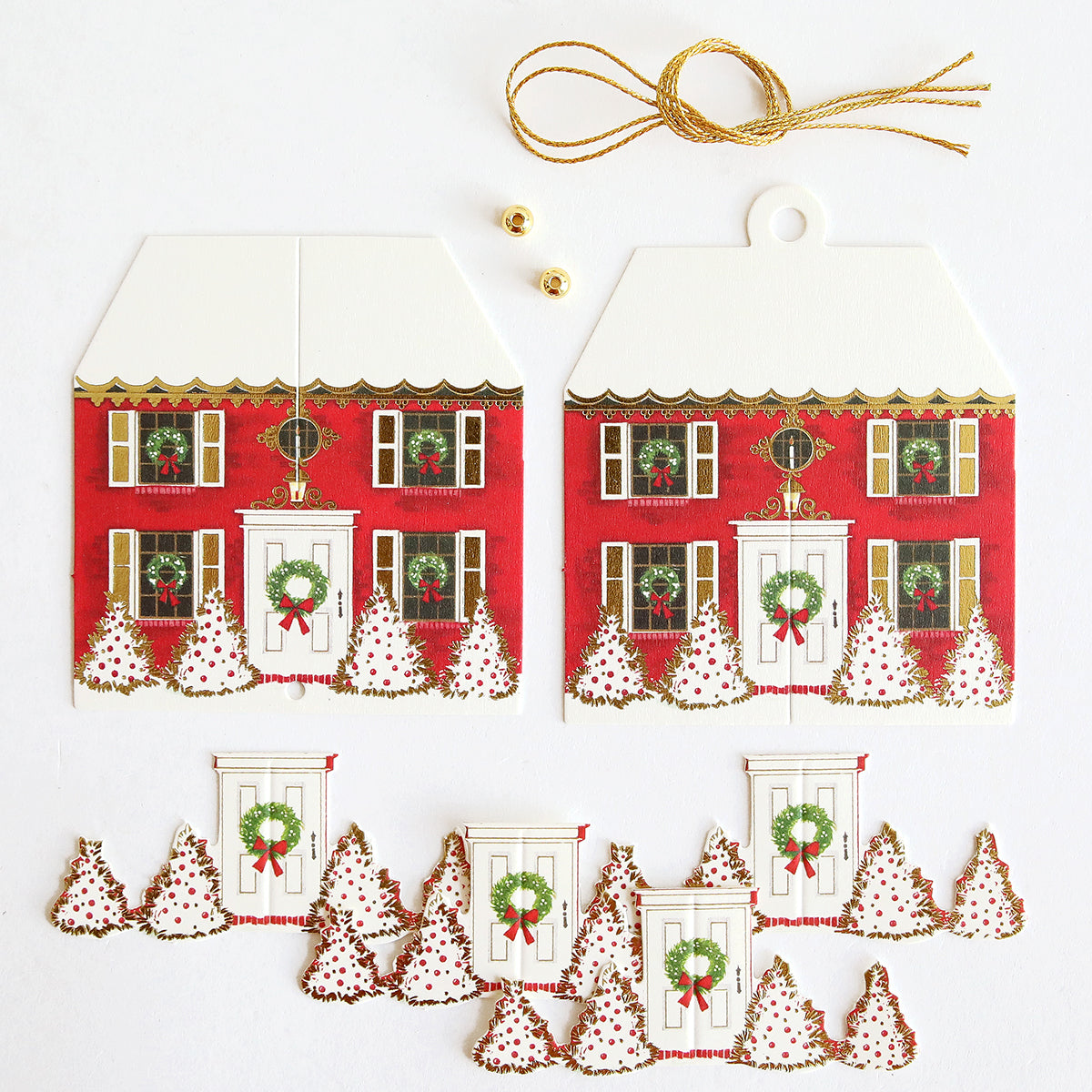 The Paper Ornaments Advent Calendar features Christmas-themed cardstock cutouts—red houses, decorated doors, trees—plus gold string, beads, and two small bells. Perfect for crafting a festive advent calendar on a white background.