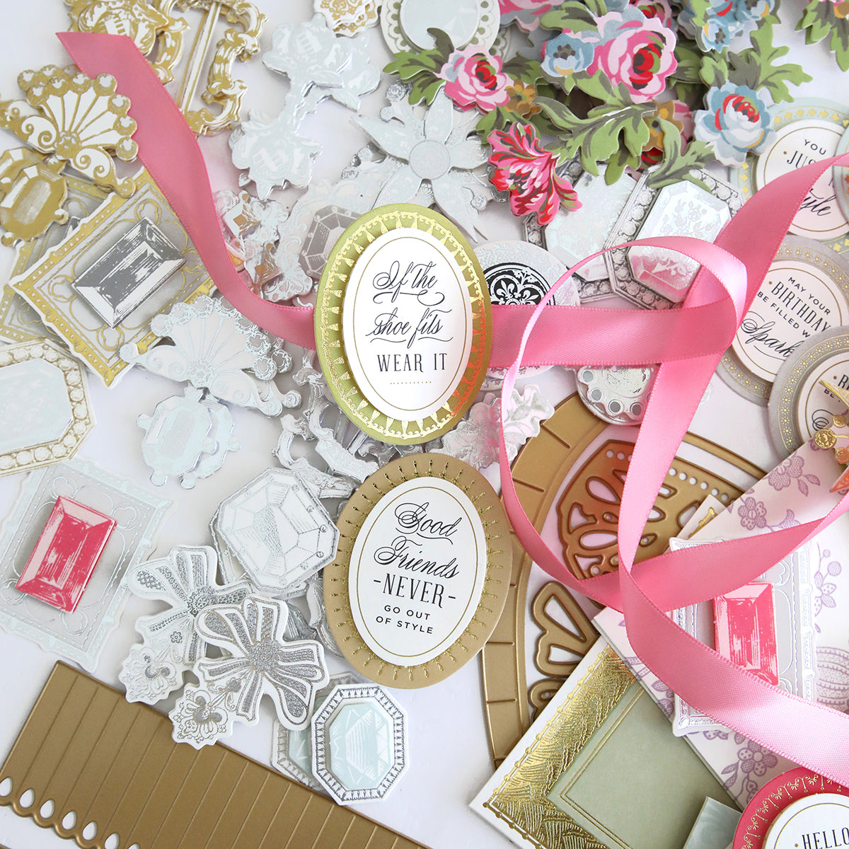 A Paper Shoes Finishing School Craft Box filled with an assortment of ribbons, paper shoes, flowers, and other items.