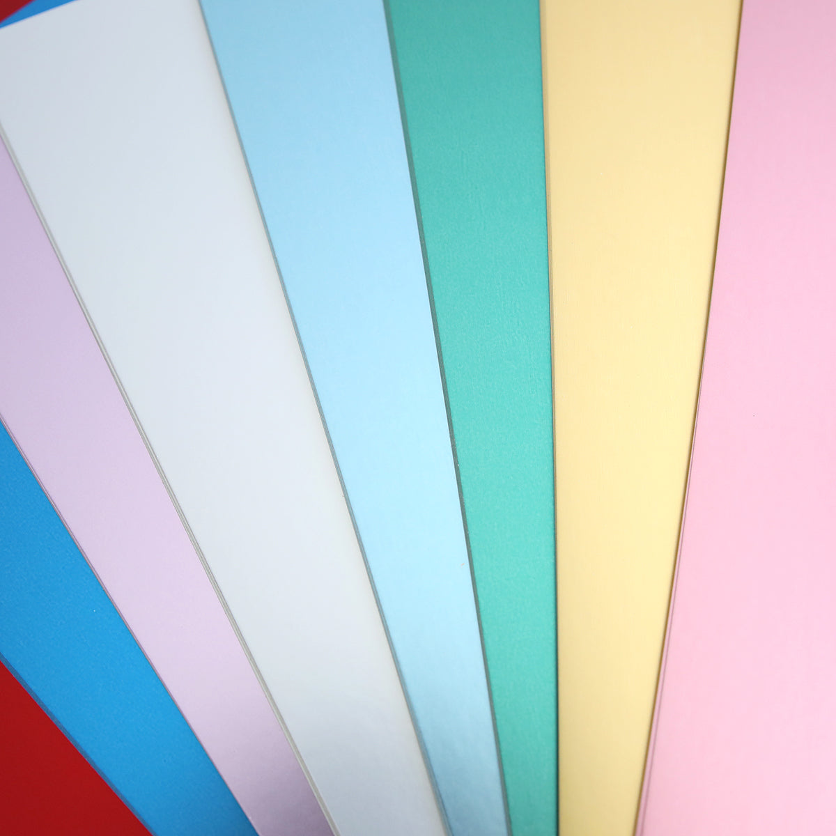 A fanned-out arrangement of colorful paper sheets in shades like blue, pink, yellow, green, and white on a red background—perfect for crafting projects with Phoebe Luxury Matte Foil Cardstock 8x12.