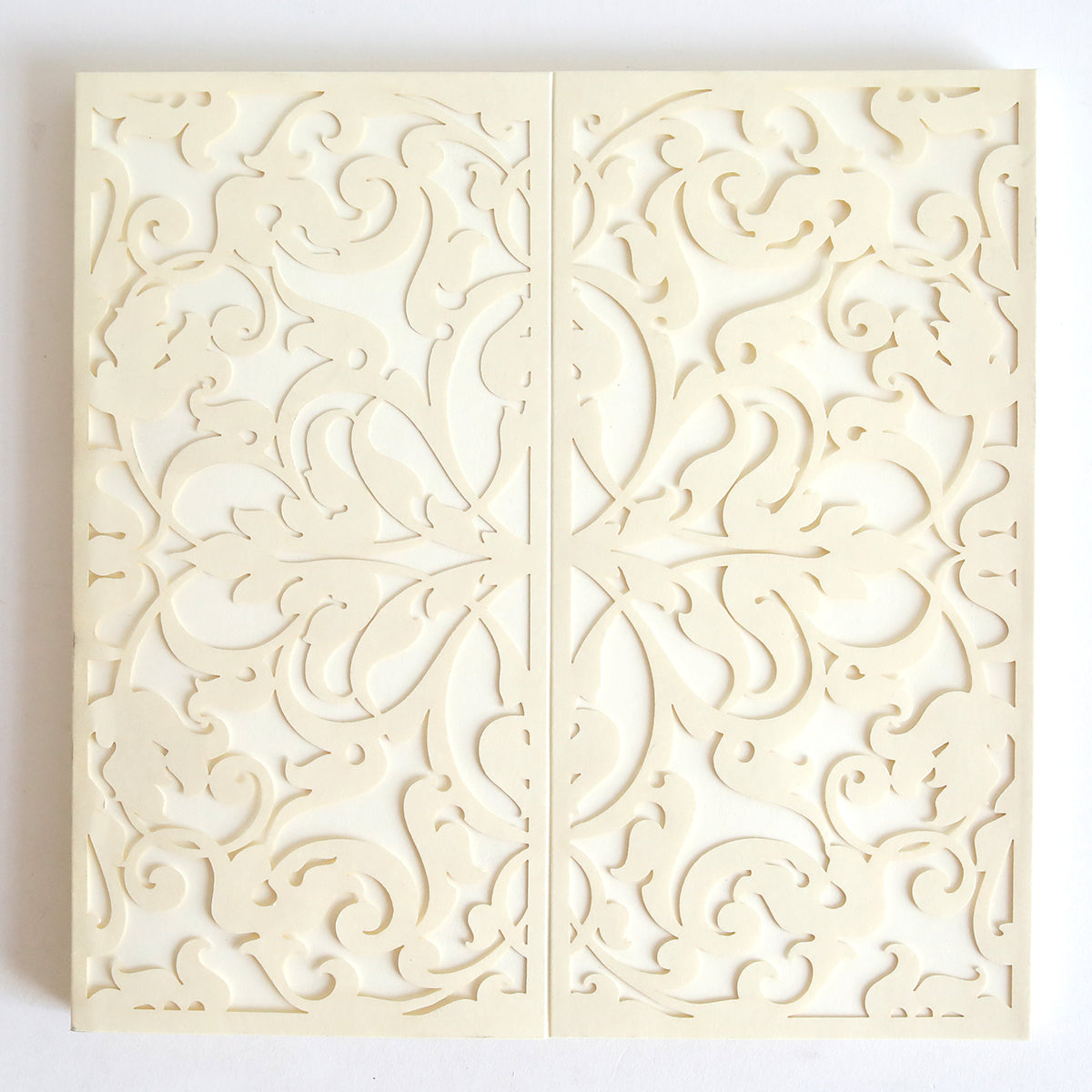The Ivory Lace Diecut Gatefold 10 pack features cream-colored cards with intricate, symmetrical floral and swirl laser-cut patterns, reminiscent of elegant ivory lace, shown closed and viewed from above.