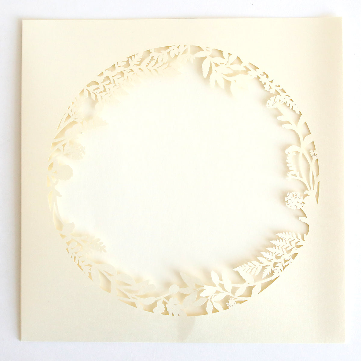The Ivory Lasercut Circle Sleeve 10 pack features cream-colored sleeves with intricate floral and leaf laser-cut borders and a circular cut-out, perfect for elegantly displaying your invitation in the blank center.