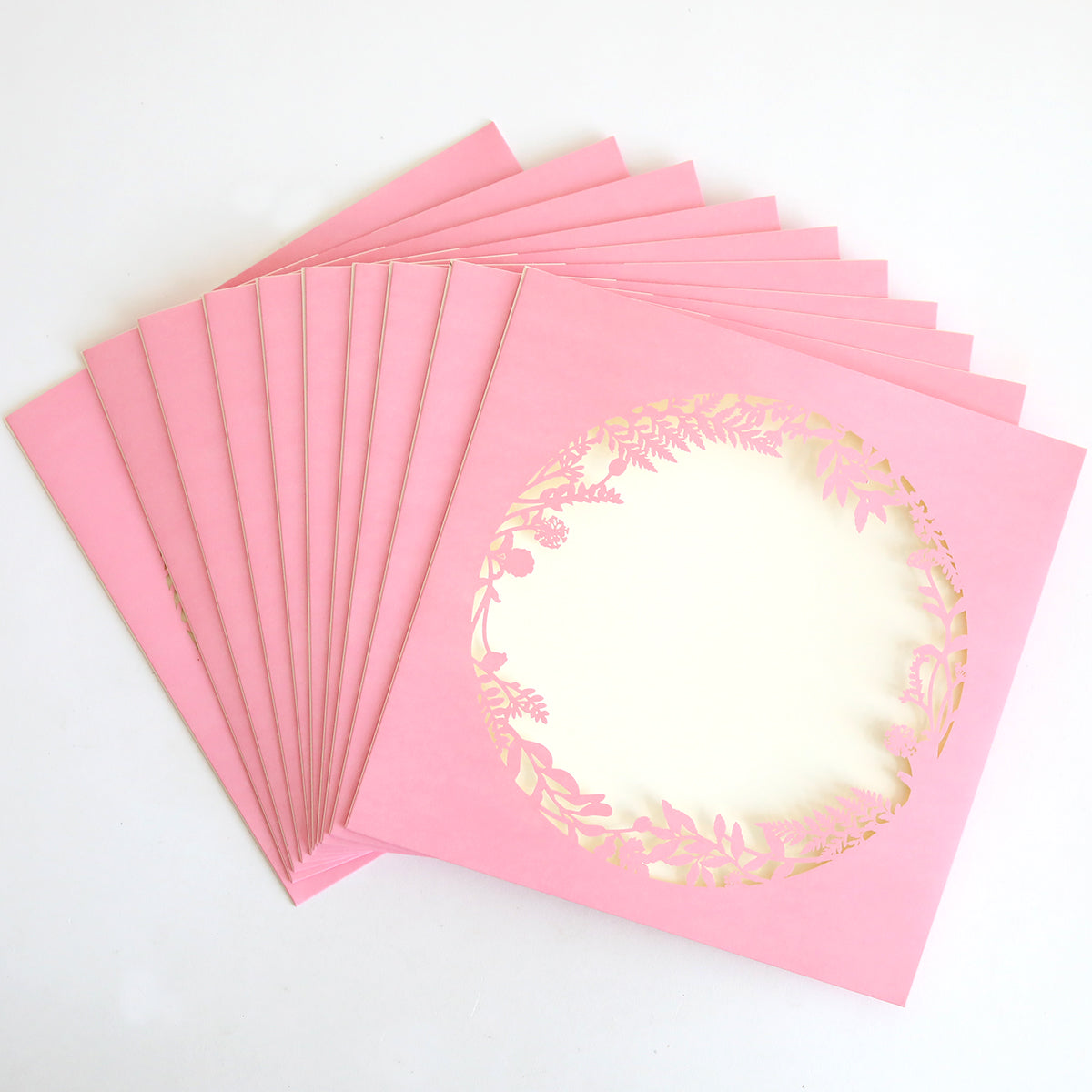 A 10-pack of Pink Lasercut Circle Sleeves, each featuring a central floral circular design, is displayed fanned out on a white background.