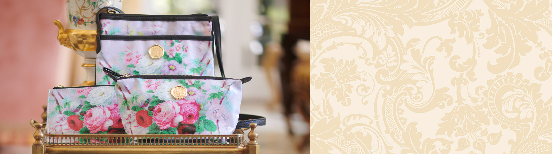 Three floral-patterned cosmetic bags with gold zippers and medallion accents are displayed on a decorative tray. A colorful, ornate vase is situated in the background.