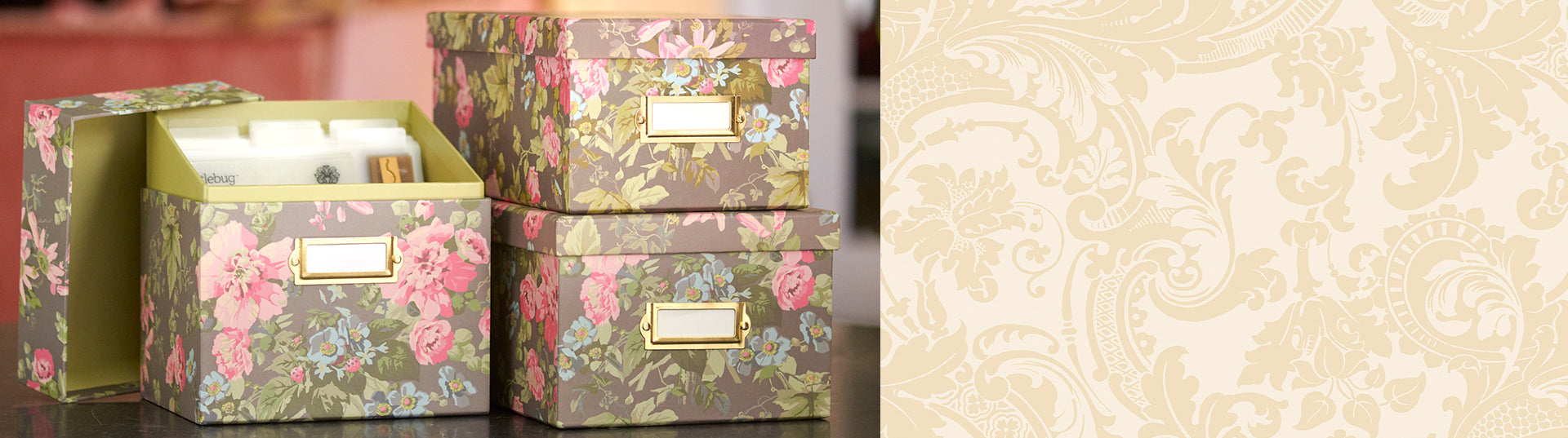 A floral-patterned box with a label holder sits open, revealing neatly organized index cards inside. The lid is propped open, and the background includes another similar box.